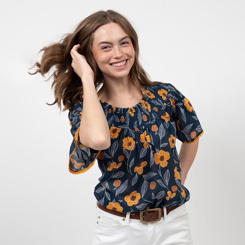 Young woman wearing a navy smocked sunflower top