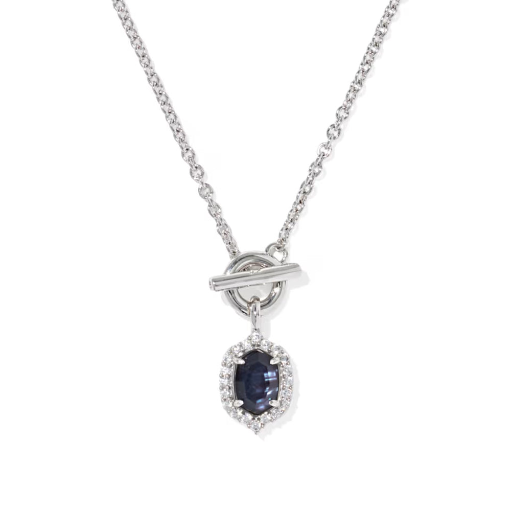 A silver chain necklace with a toggle clasp and a teardrop-shaped pendant featuring a dark blue oval gemstone surrounded by small clear stones, shown on a plain white background.