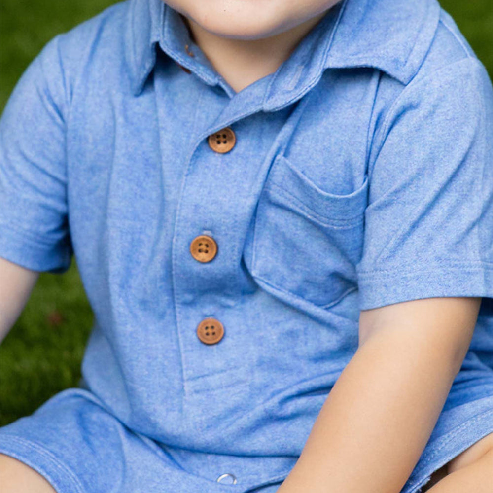 Child wearing a blue outfit with brown buttons on grass