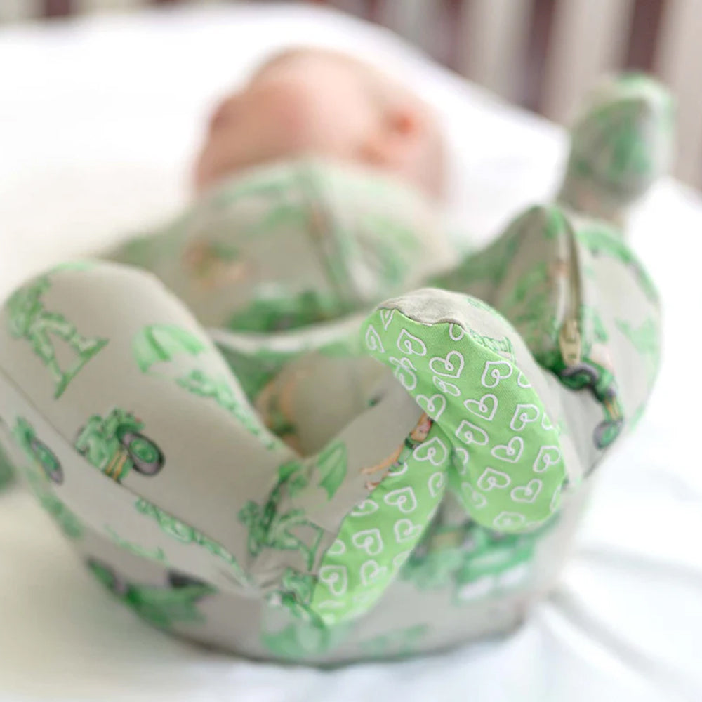Baby wearing a green and gray patterned onesie on a white background