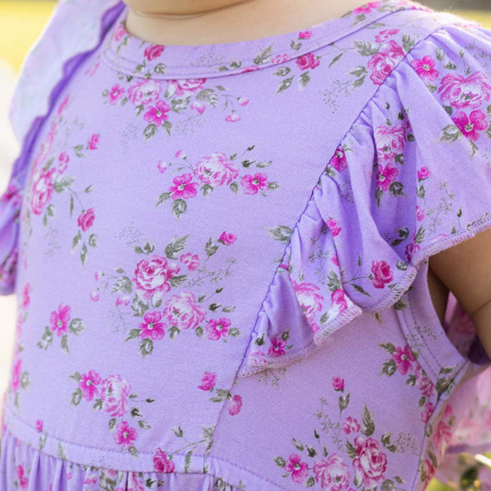 Close-up of a child's purple floral dress with ruffled sleeves.