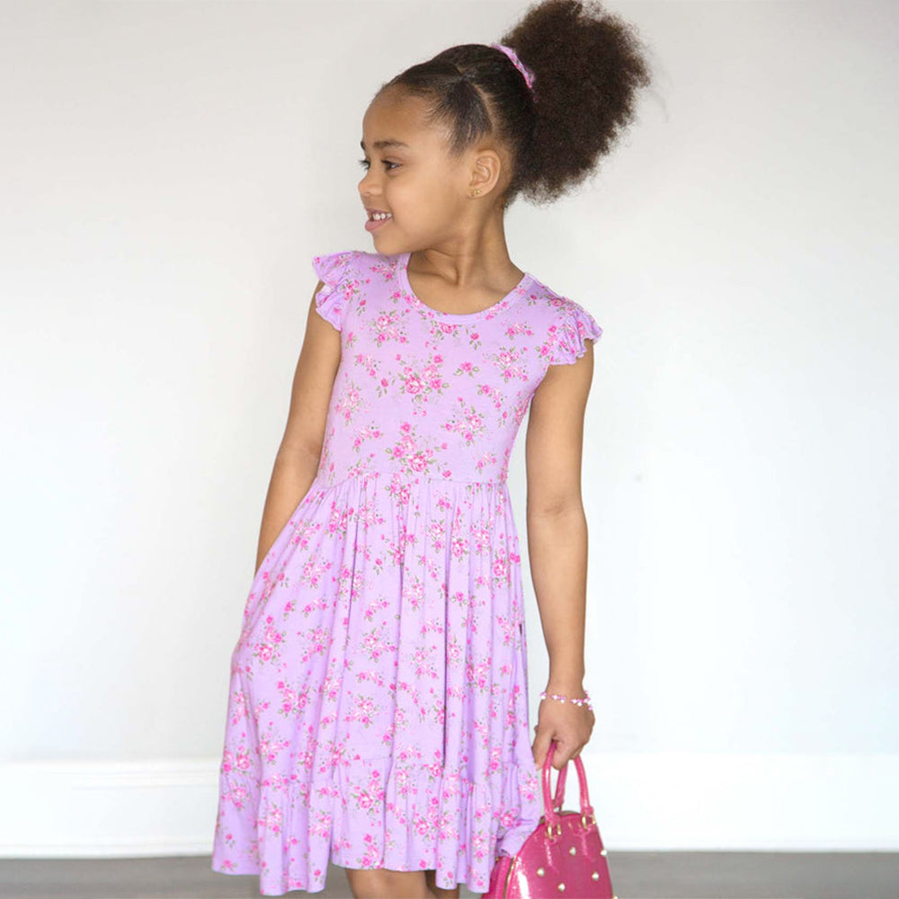 Young girl wearing a pink floral dress against a white background