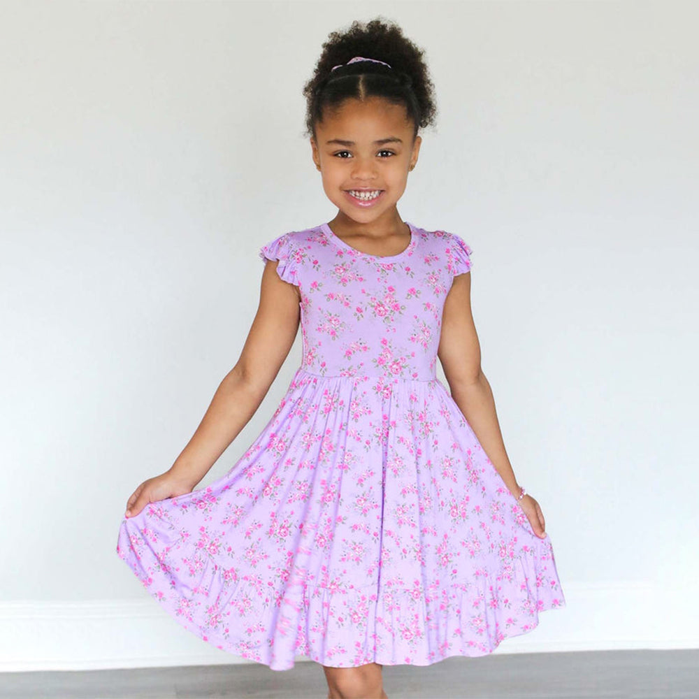 Young girl wearing a purple floral dress against a plain background