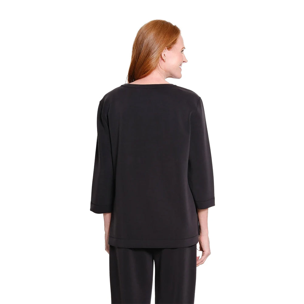 A woman with red hair is shown from the back wearing a black three-quarter sleeve top and matching black pants against a plain white background.