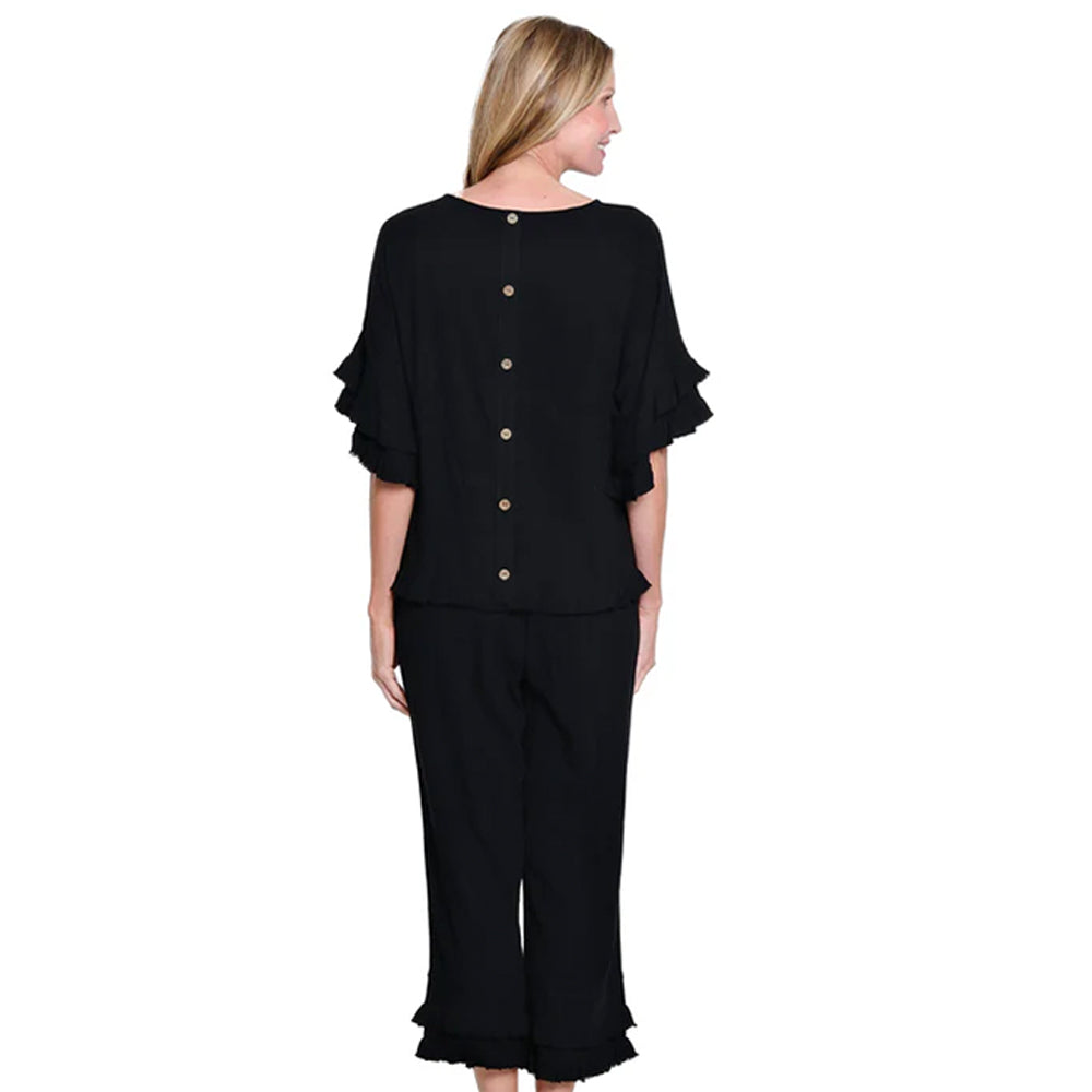 Woman wearing a black outfit with ruffled sleeves and pants on a white background