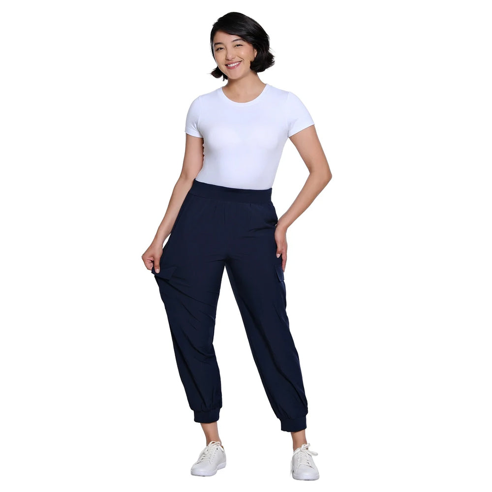 A woman modeling a white short-sleeve crewneck t-shirt and dark navy jogger pants with white sneakers, set against a solid white background.