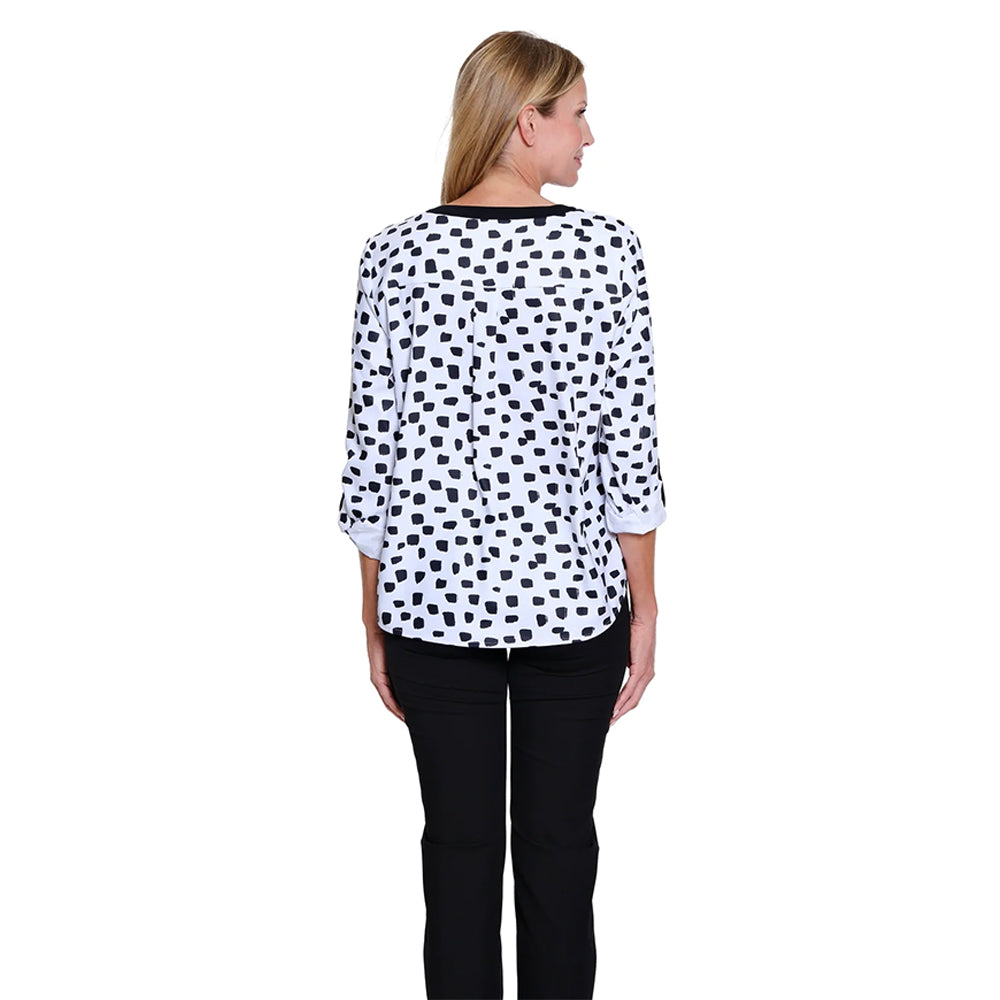 Woman wearing a polka dot blouse and black pants on a white background