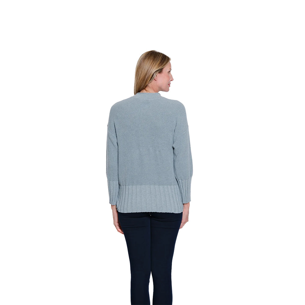 Woman wearing a light blue sweater with a textured pattern on a white background