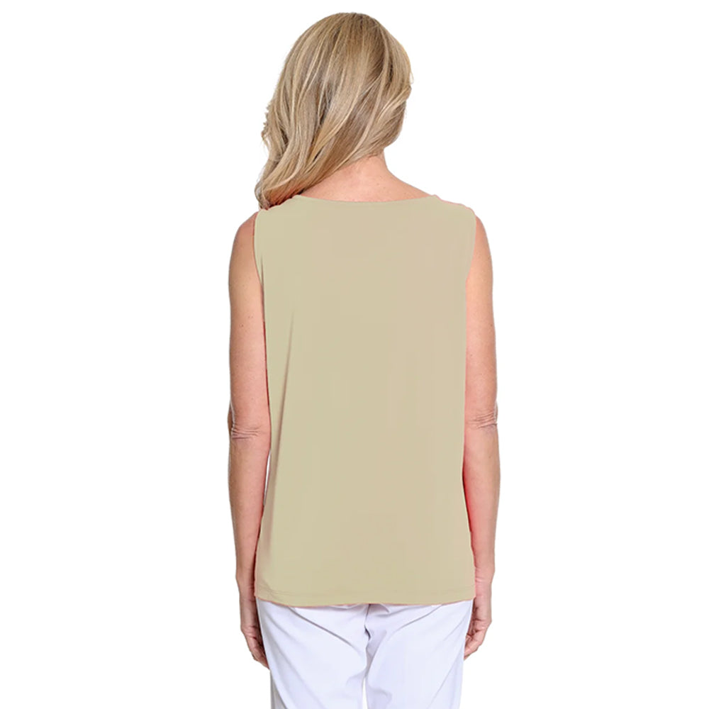 Woman wearing a beige sleeveless top and white pants on a white background