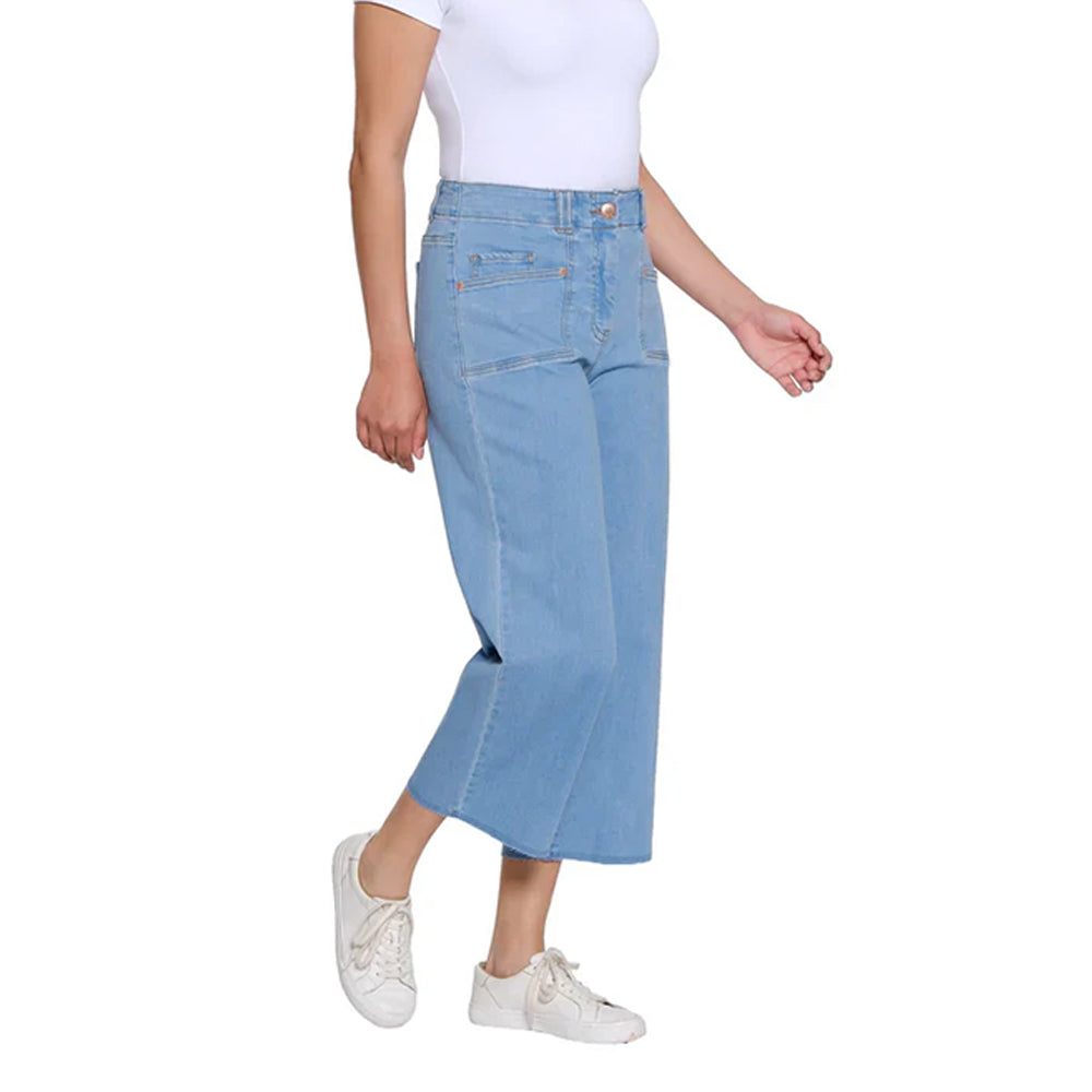 Person wearing light blue denim pants and white sneakers on a white background