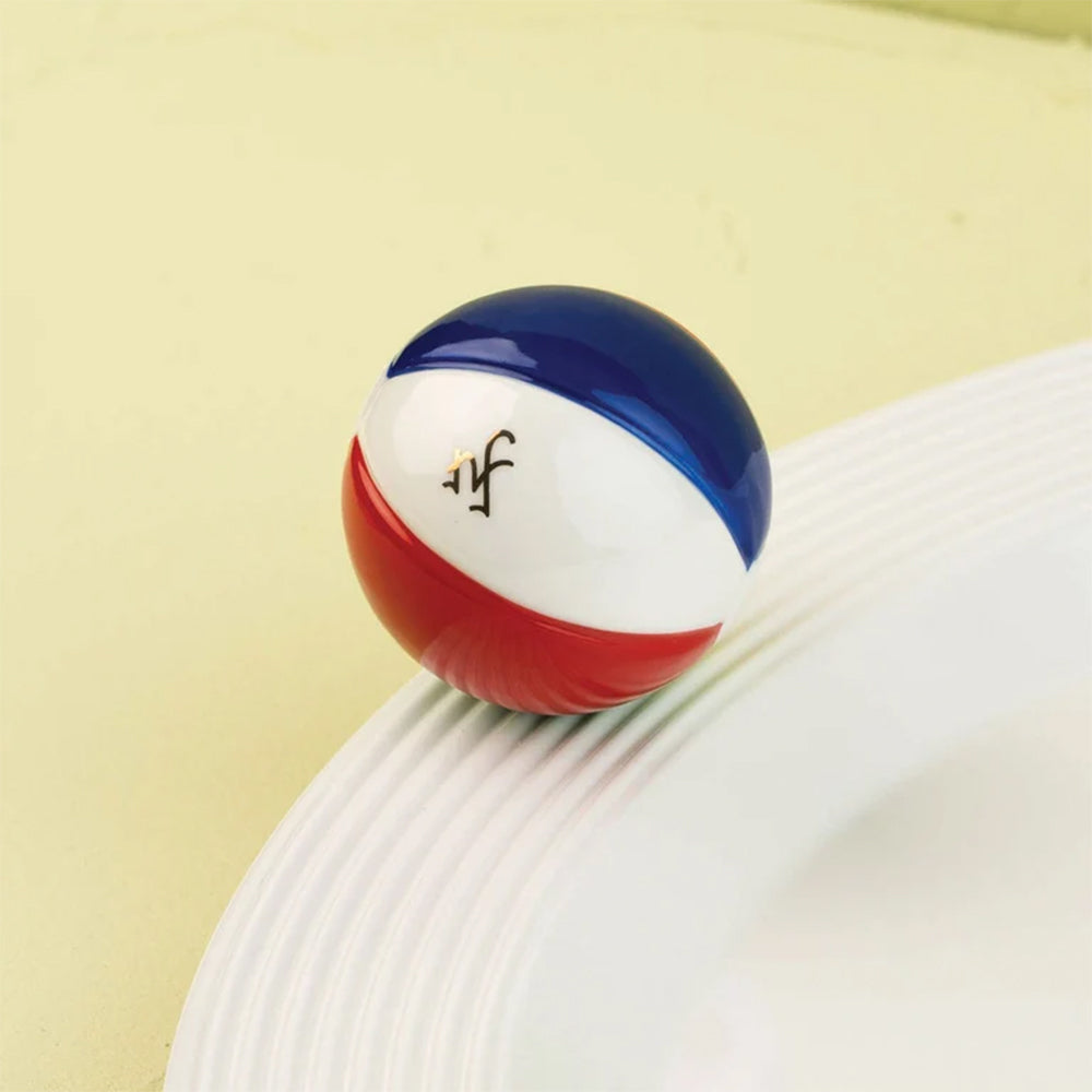 Colorful beach ball with a logo on a white surface against a beige background