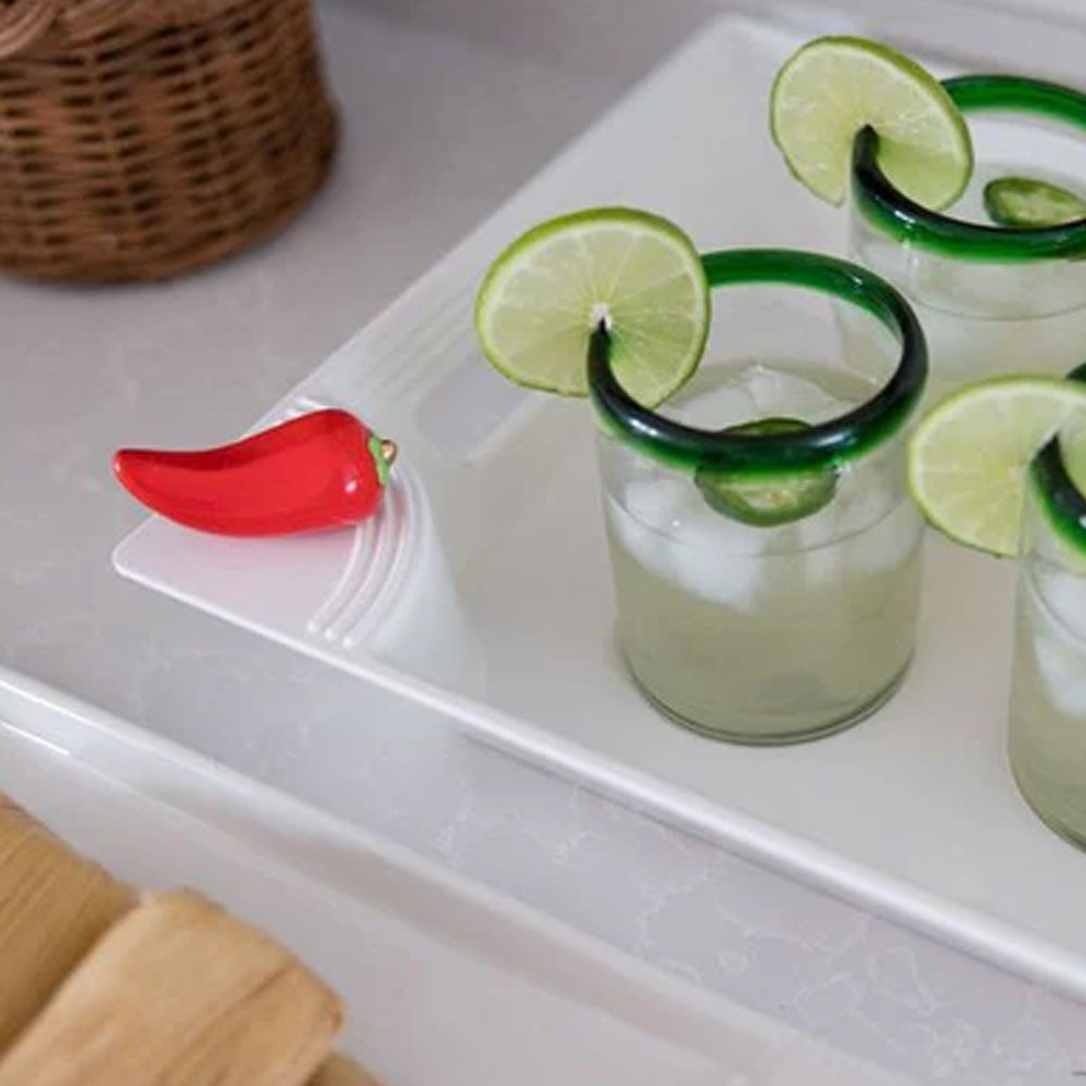 Three glasses of lime-wrapped margaritas on a white tray with a red pepper garnish.