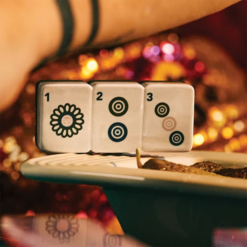 Three dice with floral and circular patterns on a table with a blurred festive background