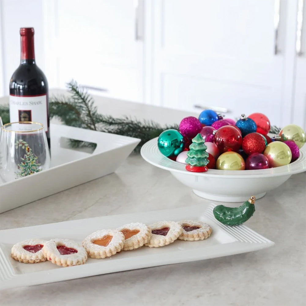 Decorative bowl with colorful ornaments, cookies on a tray, and a bottle of wine.