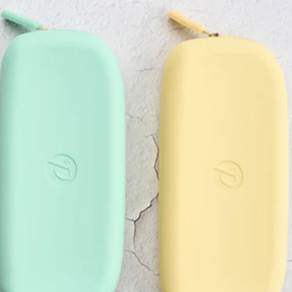 Two cylindrical silicone molds, one green and one yellow, on a textured surface.