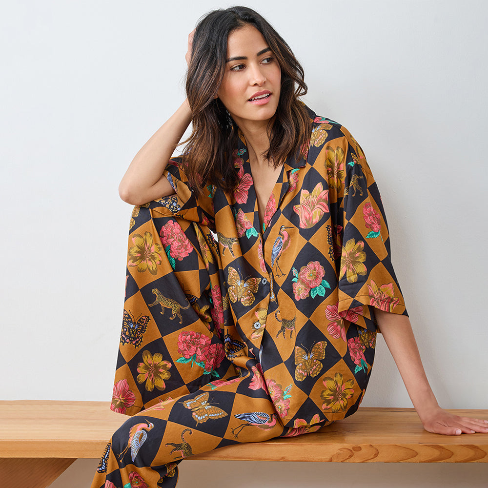 Woman wearing a colorful patterned kimono-style garment sitting on a wooden bench.