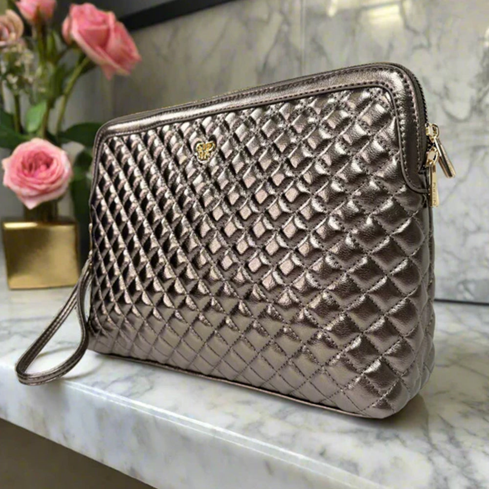 Quilted handbag on a marble surface with pink flowers in the background