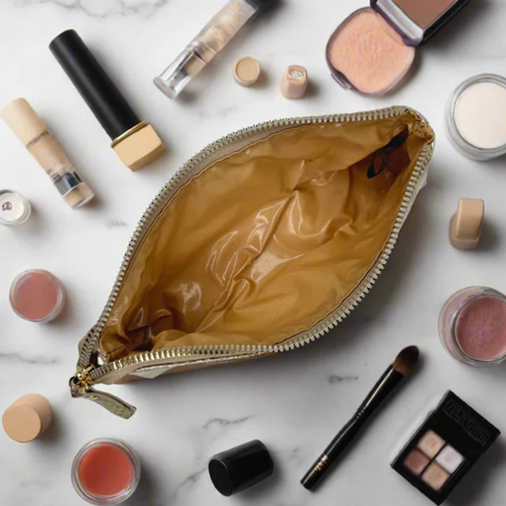Makeup bag with various makeup items on a marble surface
