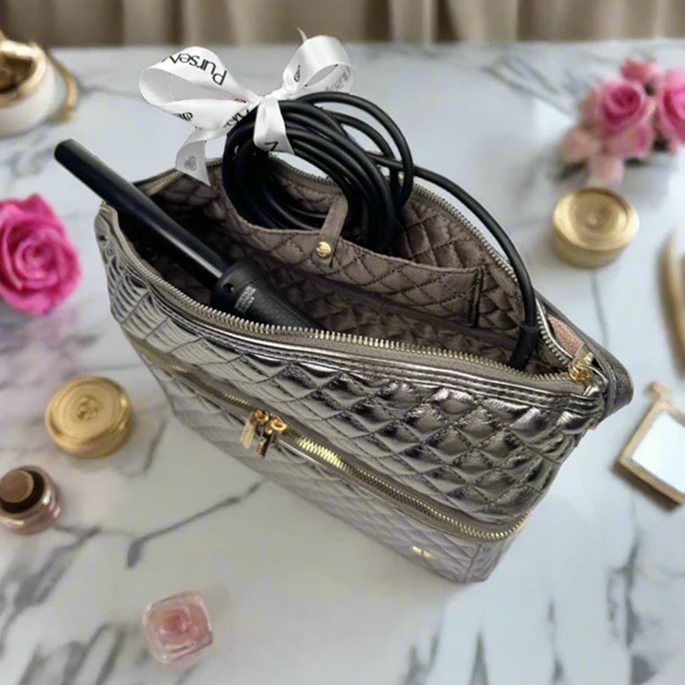 Quilted handbag with makeup items on a marble surface with flowers and candles.
