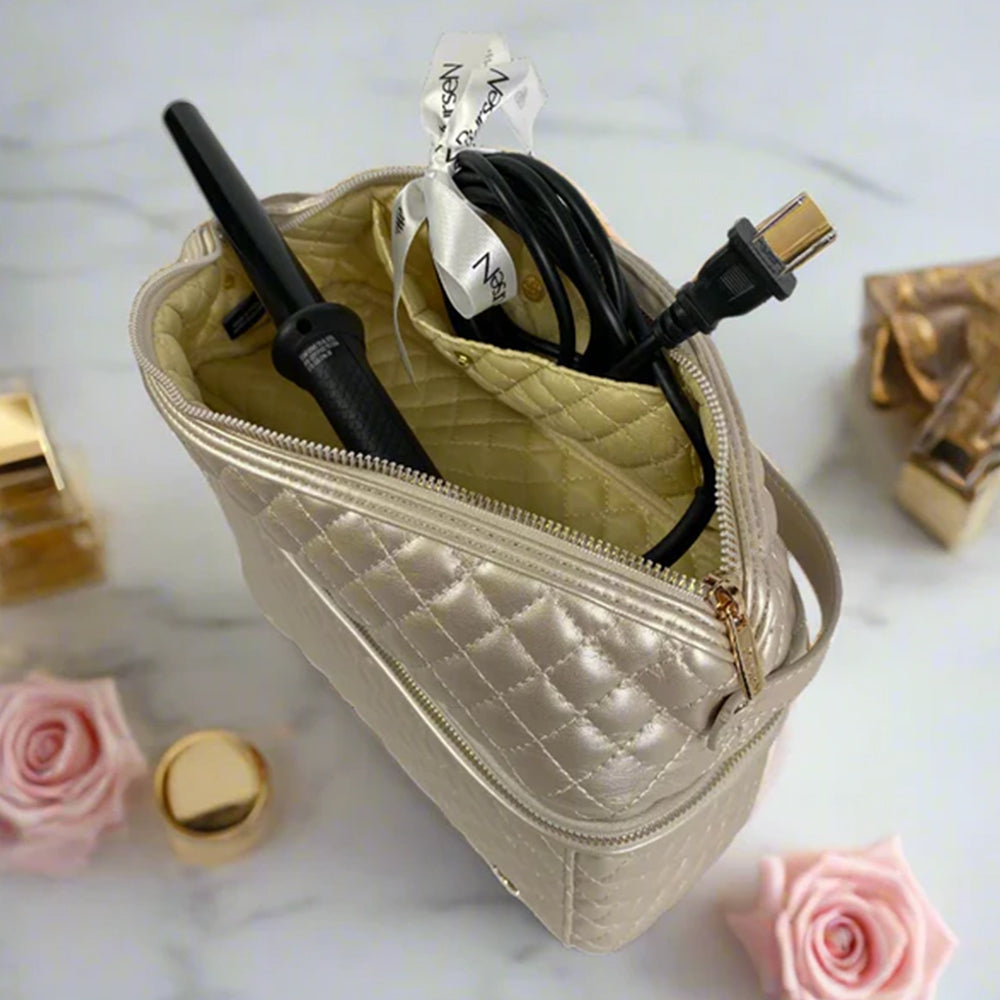 Quilted beige travel bag with hair straightener and cable on a marble surface with roses.