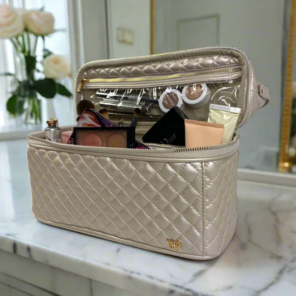 Quilted beige makeup bag with cosmetic items on a marble surface