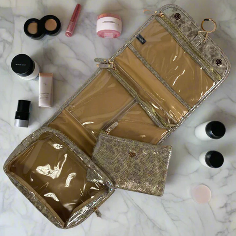 Gold cosmetic bag with makeup items on a marble surface