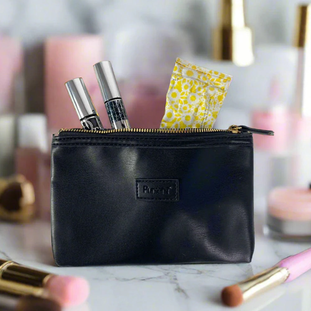 Black makeup pouch with cosmetic items on a marble surface