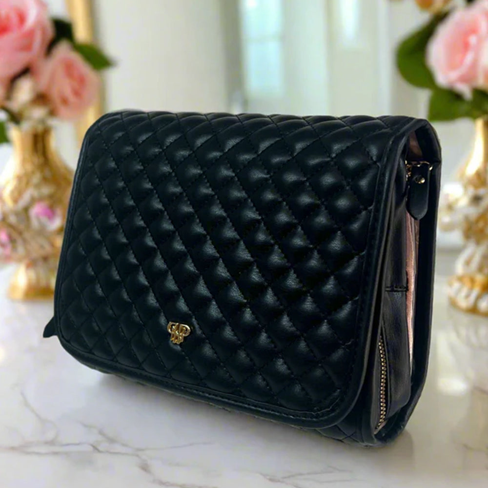 Black quilted handbag on a marble surface with floral decorations in the background
