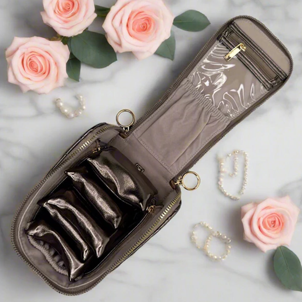 Jewelry case with compartments on a marble surface with pink roses and jewelry.