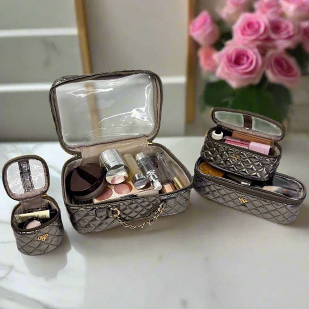 Set of quilted makeup cases with cosmetic items on a white surface, pink roses in the background.