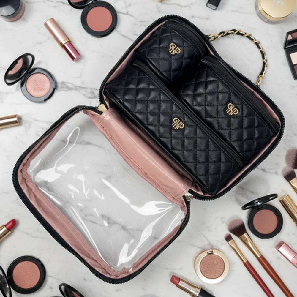 Makeup bag with quilted design and visible brand logo, surrounded by makeup items on a light background