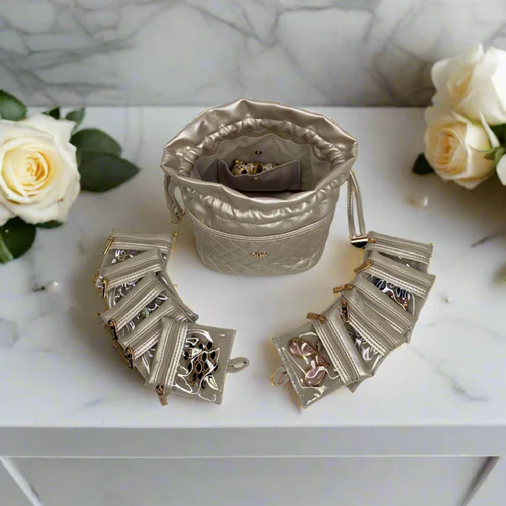 Silver jewelry set with a decorative bag on a marble surface with flowers.