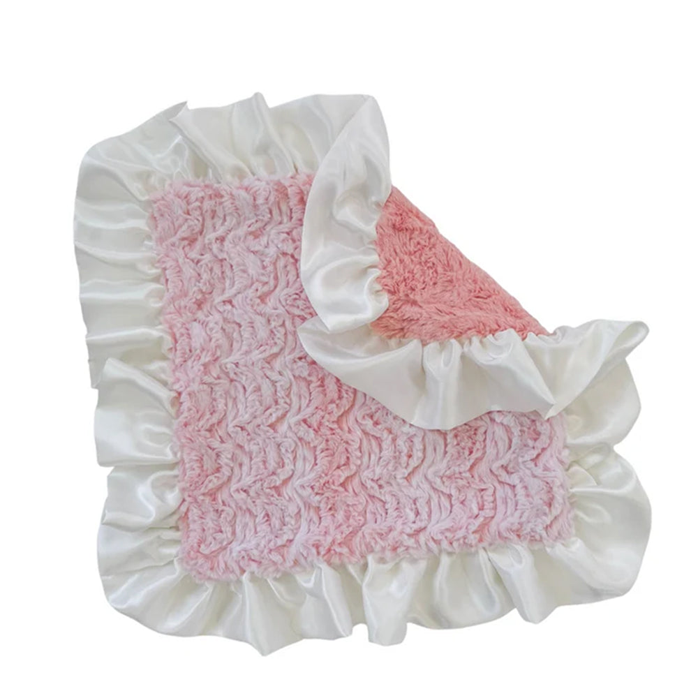A baby blanket featuring a textured pink crocheted center with white satin ruffles on all sides, shown against a plain white background.