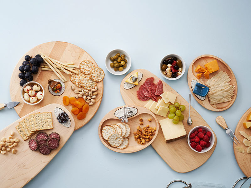 A variety of charcuterie wooden boards of crackers, sausage, olives, fruit and a cheeses on it