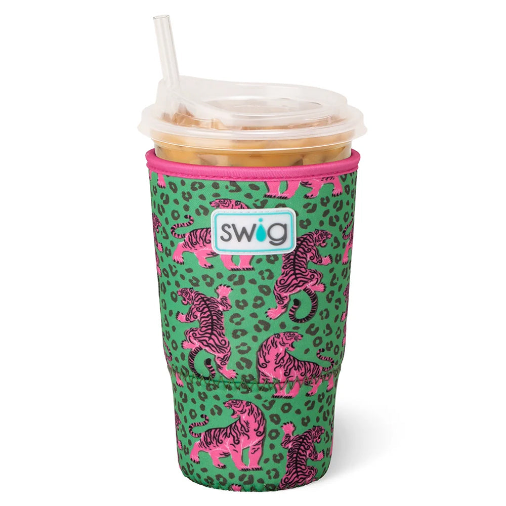 A green neoprene tumbler sleeve with a pink leopard print and pink-and-black tiger pattern, featuring a white Swig logo patch on the front. The sleeve is shown on a clear-lidded plastic cup with a straw, filled with an iced drink, against a plain white background.