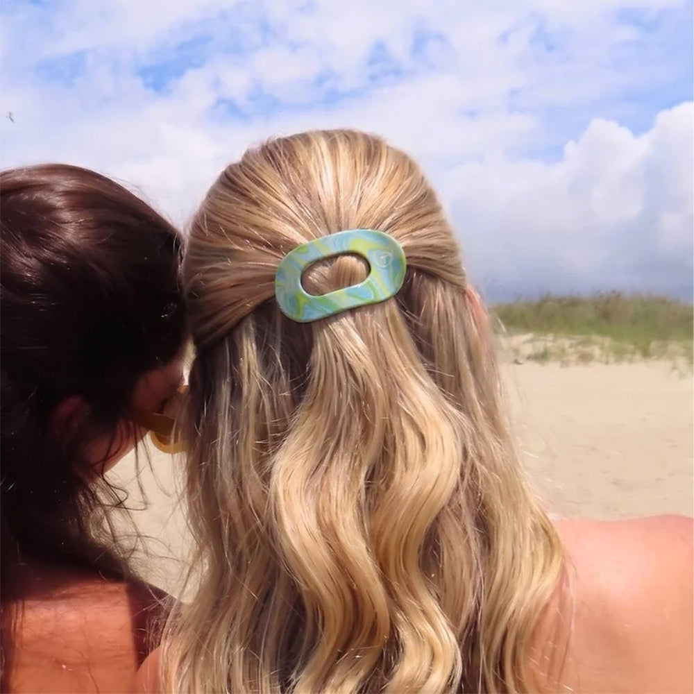 Two women on a beach with one wearing a hair clip.