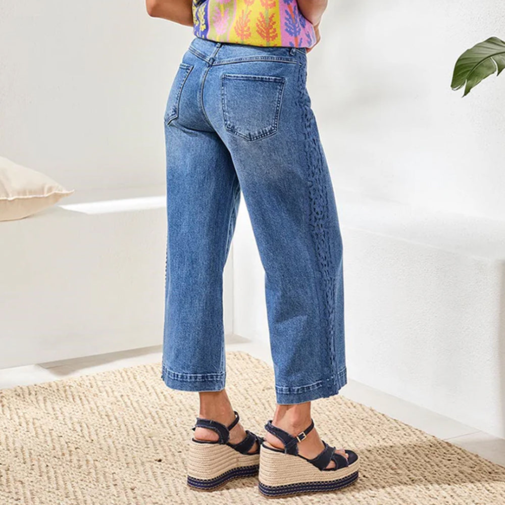 Person wearing blue jeans and a colorful top in a minimal indoor setting