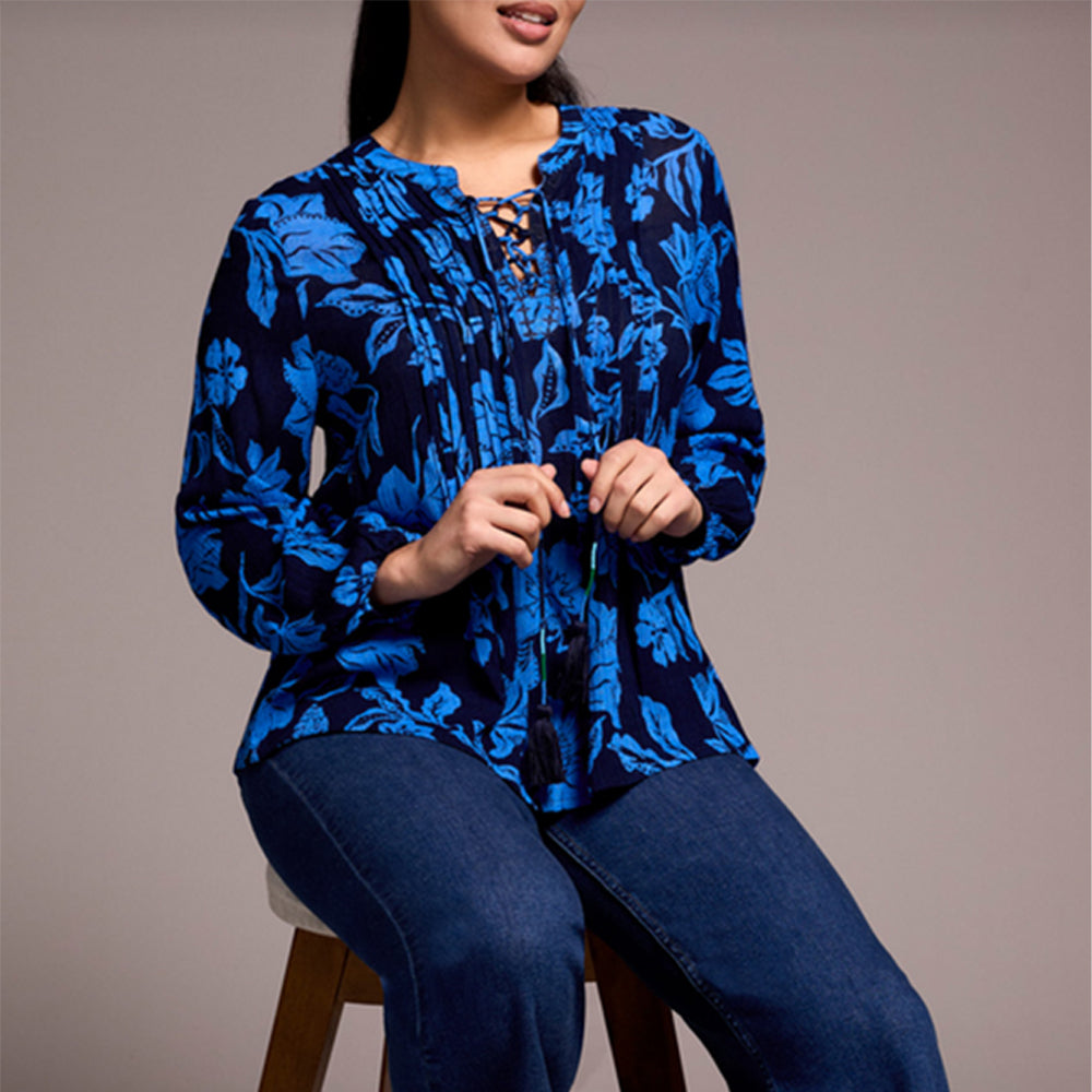 Woman wearing a blue floral blouse and jeans against a gray background