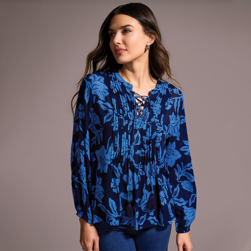 Woman wearing a blue floral patterned blouse against a gray background