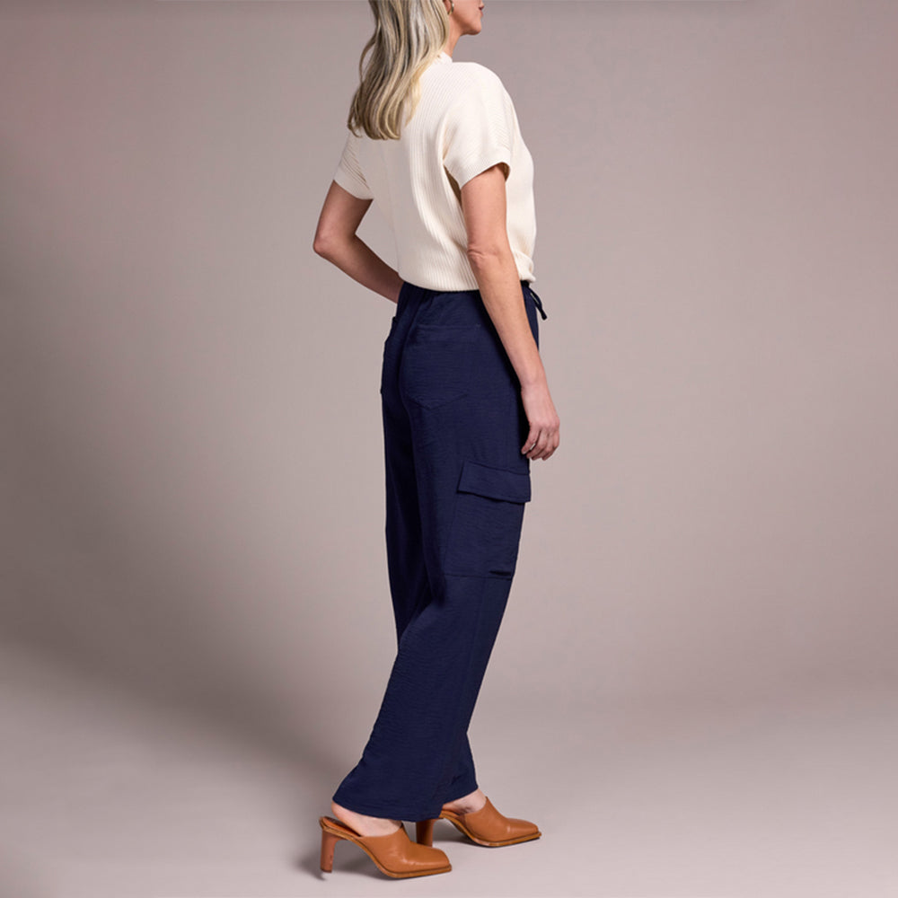 Person wearing navy cargo pants and a white top on a plain background