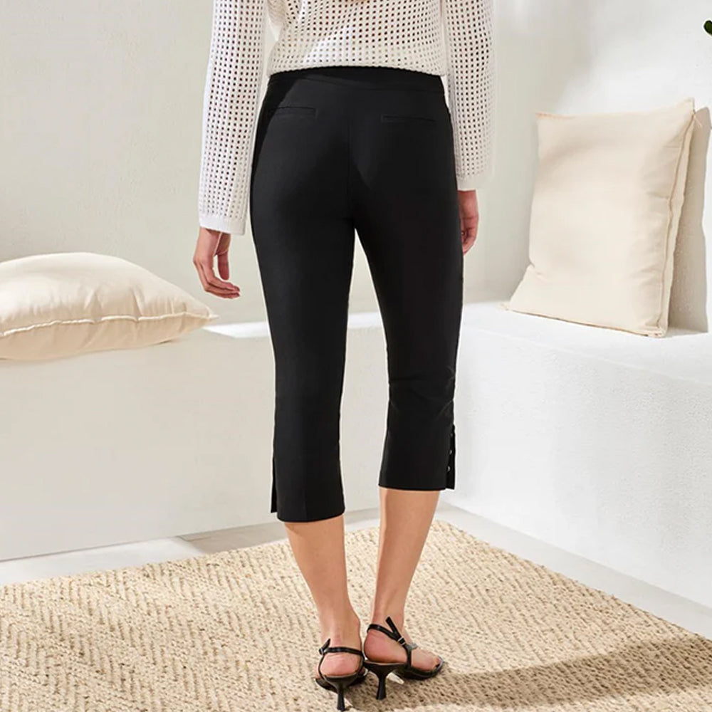 Person wearing black capri pants in a minimalistic room with white walls and a white sofa.