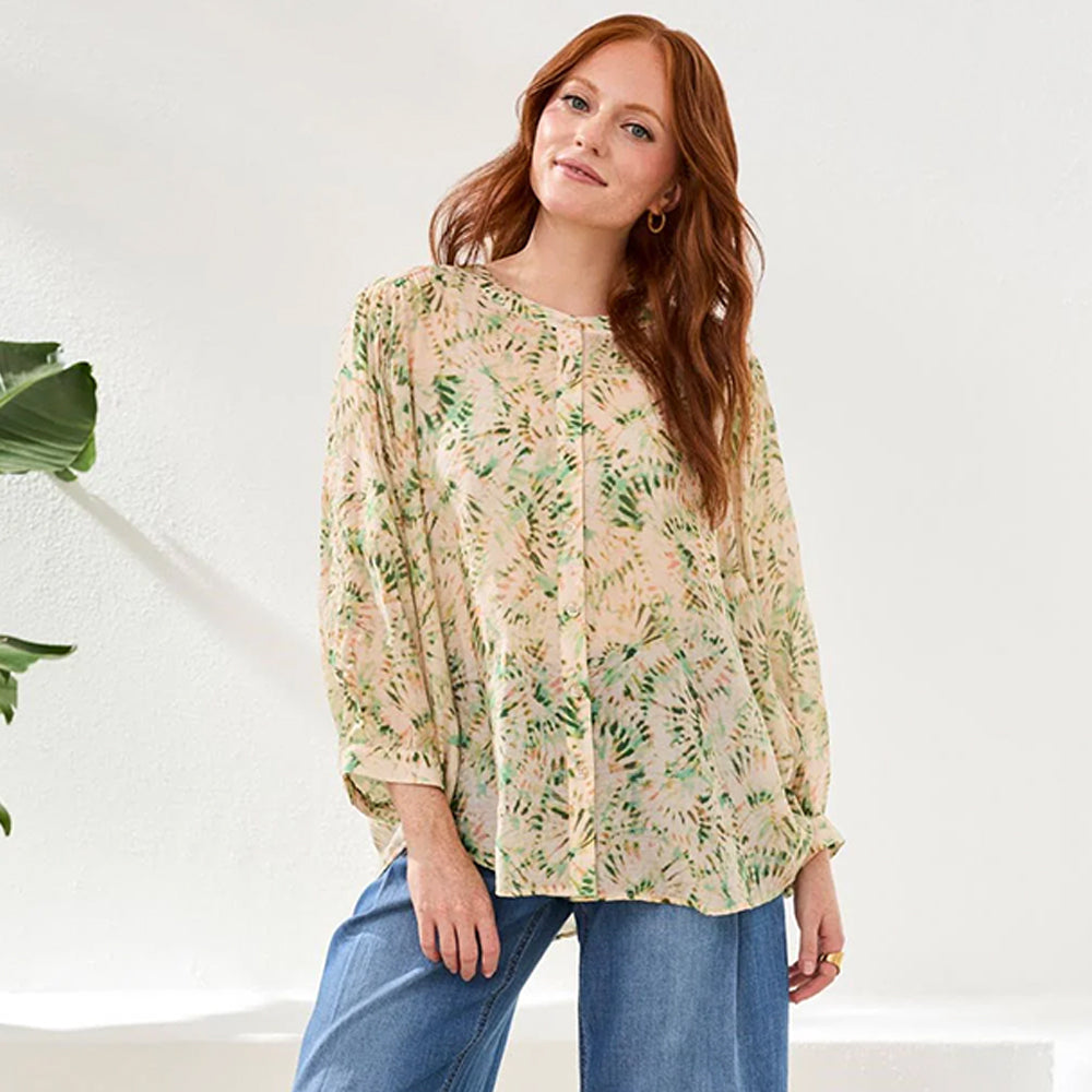 Woman wearing a floral blouse and jeans against a white background