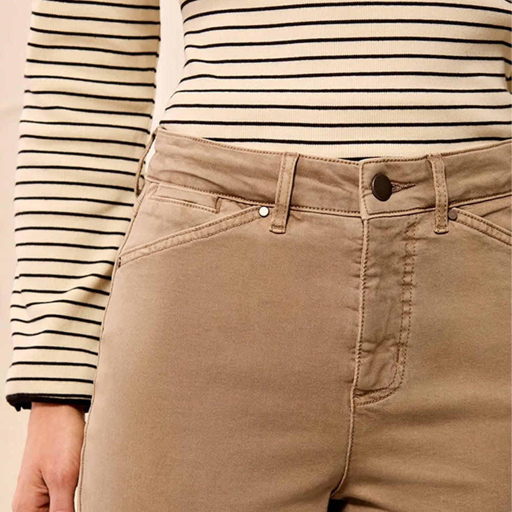 Close-up of a person wearing tan straight-leg denim jeans with a black and cream striped long-sleeve top, showing the waistband, belt loops, button, and front pocket details.