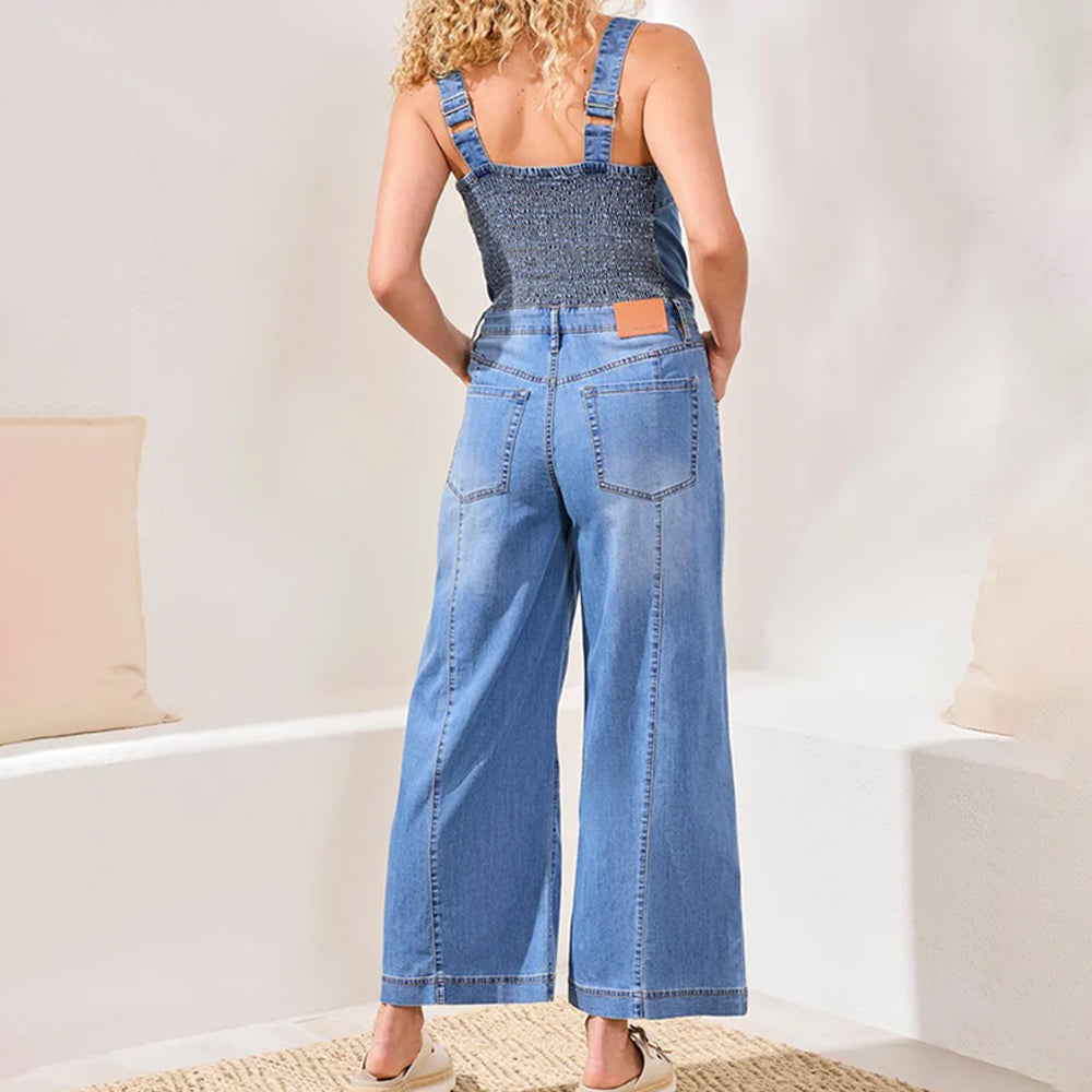 Person wearing blue denim overalls in a minimal indoor setting