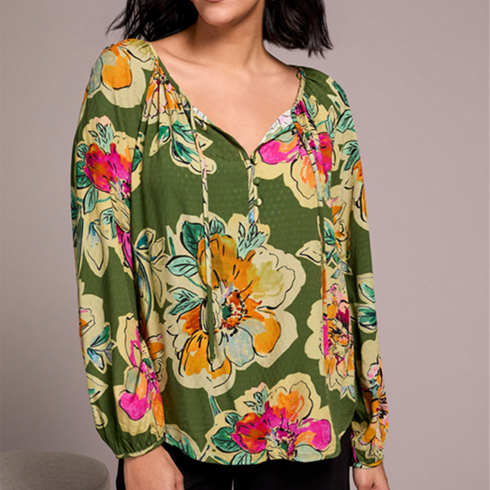 Woman wearing a green floral blouse against a plain background