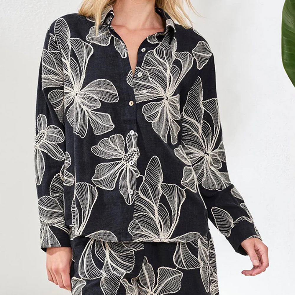 Black shirt with white floral pattern worn by a person on a white background
