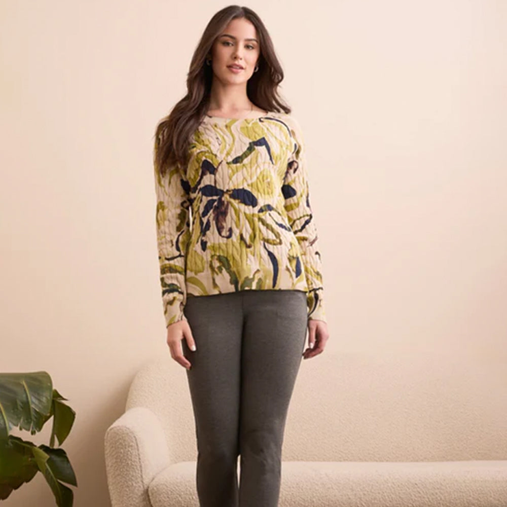 Woman wearing a floral sweater and gray pants against a beige background