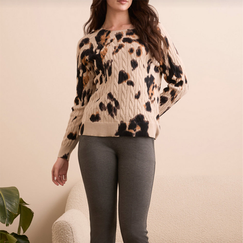 Woman wearing a leopard print sweater and gray leggings against a beige background