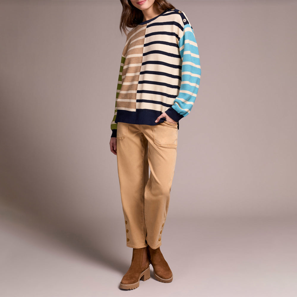 Person wearing a striped sweater and beige pants on a plain background