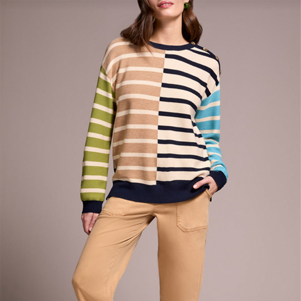 Person wearing a multicolored striped sweater and beige pants against a plain background